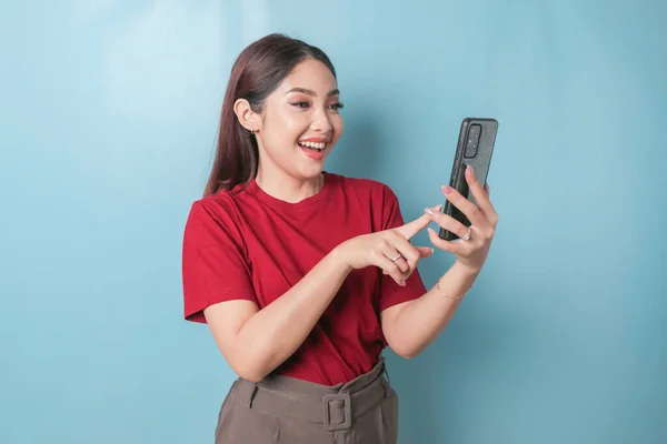 Excited Asian Woman Wearing Red Shirt Pointing Her Smartphone Isolated — Fotografia de Stock