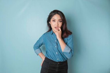 Portrait of chic attractive adorable gorgeous charming sexy Asian woman biting forefinger isolated over blue background