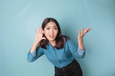 Amazed curious bride young woman wearing a blue shirt trying to hear you overhear listening intently isolated on blue turquoise background studio portrait.