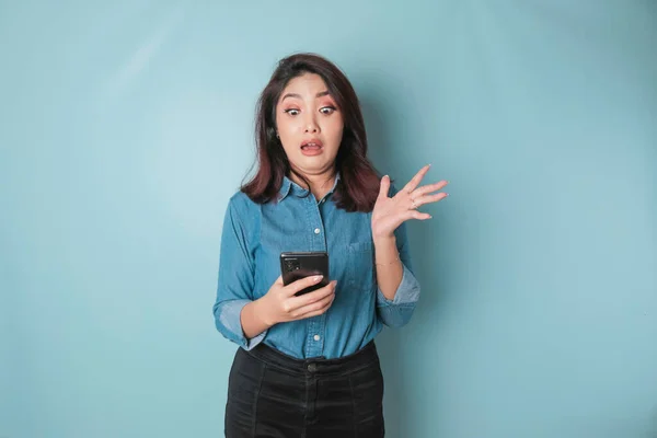 Έκπληκτη Ασιάτισσα Που Φοράει Μπλε Πουκάμισο Δείχνοντας Smartphone Της Απομονωμένη — Φωτογραφία Αρχείου