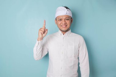 Excited Balinese man wearing udeng or traditional headband and white shirt giving number 12345 by hand gesture