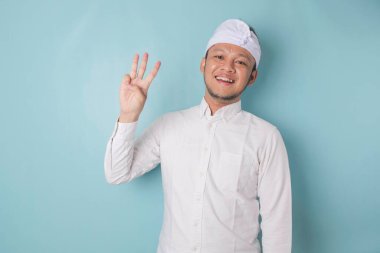 Excited Balinese man wearing udeng or traditional headband and white shirt giving number 12345 by hand gesture