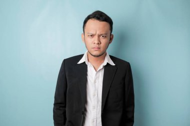 Cool businessman wearing black suit standing on blue background