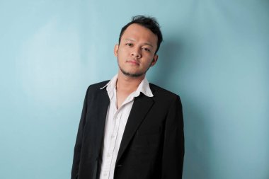 Cool businessman wearing black suit standing on blue background