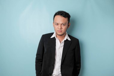 Cool businessman wearing black suit standing on blue background