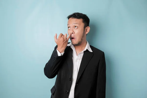 Asian Man Wearing Black Suit Picking His Nose Isolated Blue — Stok Foto