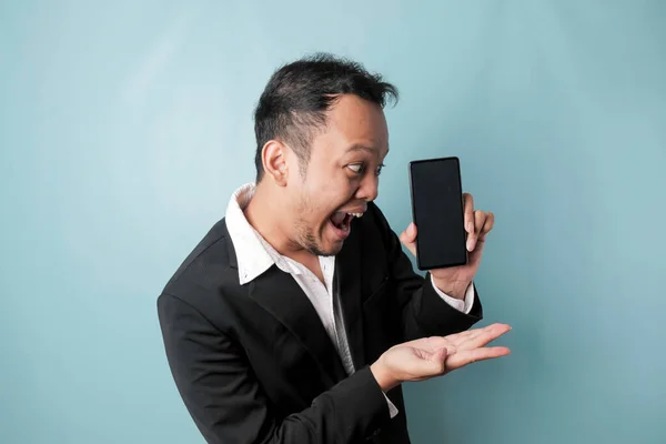 Surprised Asian Businessman Wearing Black Suit Holding His Smartphone Showing — ストック写真