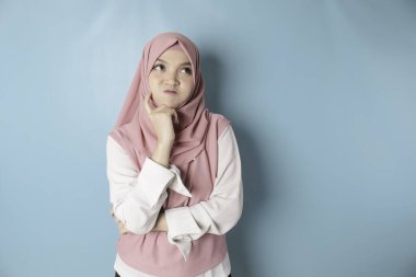 Portrait of a thoughtful young Muslim woman wearing pink hijab looking aside