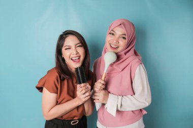 two pretty young Asian women holding ladle for having fun, friendship concept.