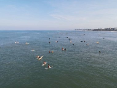 Aerial view of people surfing on waves with surfboards when vacation in Bali, Indonesia .