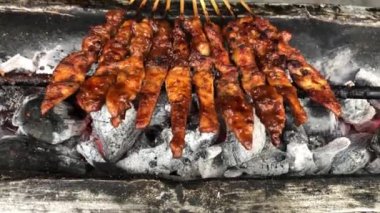 Geleneksel kömür ateşinde tavuk satay. Duman ve iştah açıcı bir bakışla alev alev yanıyordu. Eller ızgarada satay pişiriyor.