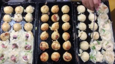 Şef, takoyaki tavasından Japon aperatifleri alıyor. Geleneksel Japon köftesi pişirme.