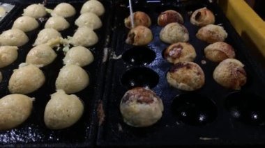 Şef, takoyaki tavasından Japon aperatifleri alıyor. Geleneksel Japon köftesi pişirme.