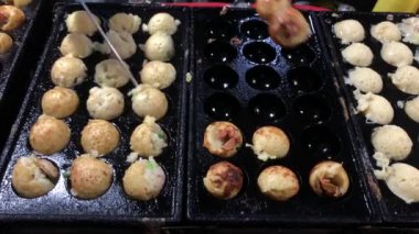 Şef, takoyaki tavasından Japon aperatifleri alıyor. Geleneksel Japon köftesi pişirme.