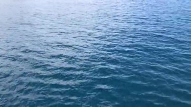Sakin mavi deniz dalgaları, günbatımı ışığı geminin arkasında..