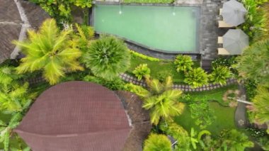 Top aerial view of swimming pool in resort with tropical garden in Bali, Indonesia