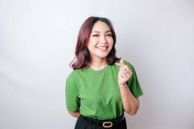 Yeşil tişört giyen çekici genç Asyalı bir kadın mutlu ve romantik şekilli bir kalp hareketi şefkatli duygular ifade eder.