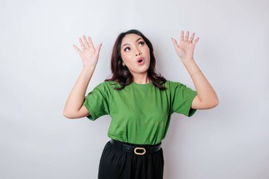 Şok olmuş Asyalı kadın yeşil tişört giyip fotokopi odasını işaret ediyor, beyaz arka planla izole edilmiş.