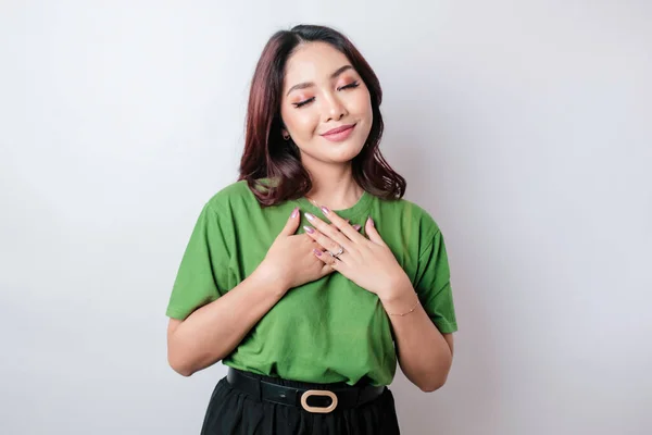 Mutlu, düşünceli, genç bir kadın, beyaz arka planda yalnız gülümsüyor.