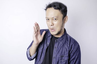 Asyalı genç adam lacivert gömlek giyiyor, ağızdan ağıza konuşuyor, gizli söylentiler yayıyor, kötü niyetli konuşmalar fısıldıyor.