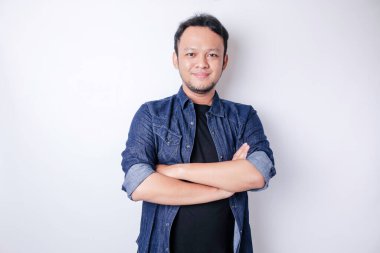 Kollarını kavuşturup beyaz arka planda izole edilmiş kameraya bakan kendinden emin gülümseyen Asyalı bir adamın portresi.