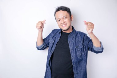 Lacivert tişört giyen çekici bir Asyalı genç adam mutlu olur ve romantik şekilli bir kalp hareketi şefkatli duygular ifade eder.