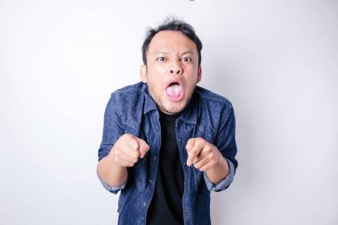 Tatmin olmamış Asyalı genç bir adam, mavi denizci gömleği giymiş, asık surat ifadeleri takınarak huysuz görünür.