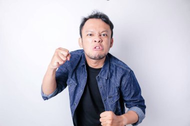 Tatmin olmamış Asyalı genç bir adam, mavi denizci gömleği giymiş, asık surat ifadeleri takınarak huysuz görünür.