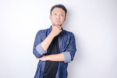 Düşünceli genç Asyalı bir adamın portresi lacivert gömlek giyiyor ve seçenekleri gözden kaçırıyor.