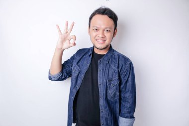 Heyecanlı, mavi tişörtlü Asyalı adam beyaz bir arkaplan tarafından izole edilmiş el hareketi yapıyor.