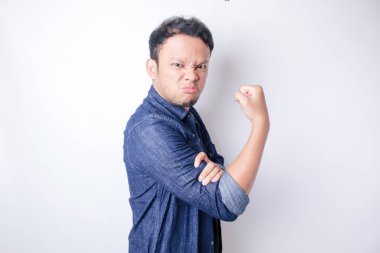 Heyecanlı Asyalı adam kollarını ve kaslarını gururla kaldırarak güçlü bir hareket sergiliyor.