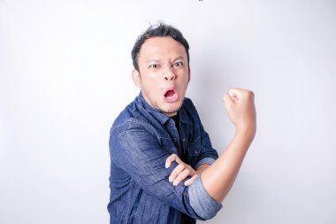 Heyecanlı Asyalı adam kollarını ve kaslarını gururla kaldırarak güçlü bir hareket sergiliyor.