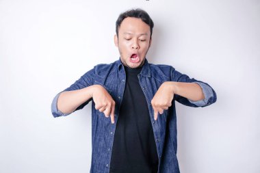 Şok olmuş Asyalı adam mavi donanma tişörtü giymiş. Altındaki fotokopi alanını işaret ediyor. Beyaz arka planla izole edilmiş.