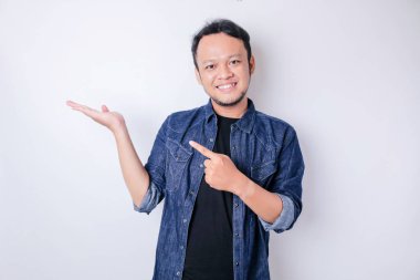 Gülümseyen yakışıklı Asyalı adam boş alanı işaret ediyor izole edilmiş beyaz arka plan