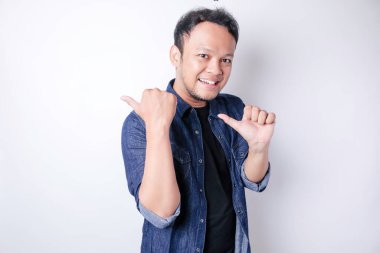 Gülümseyen yakışıklı Asyalı adam boş alanı işaret ediyor izole edilmiş beyaz arka plan