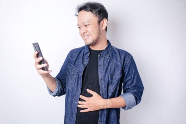 Mutlu Asyalı adam elini karnına koyuyor. Lezzetli bir akşam yemeğinden sonra karnını doyuruyor. Telefonunu tutarken çok düşünceli..