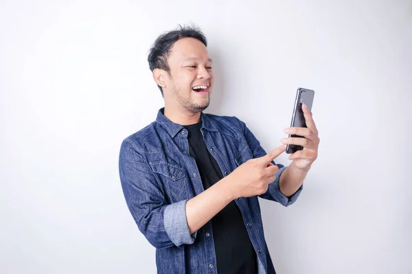 笑顔のアジア人男性の肖像画は笑顔で 白い背景によって隔離されたネイビーブルーのシャツを着てスマートフォンを持っています — ストック写真
