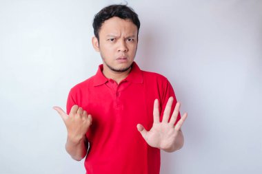 El hareketleriyle çekici Asyalı adam, yan tarafındaki fotokopi alanını gösterirken reddedilme ya da yasaklama pozu veriyor.