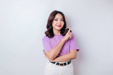 Heyecanlı Asyalı kadın eflatun tişört giyiyor. Fotokopi odasını işaret ediyor. Beyaz arka planla izole edilmiş.