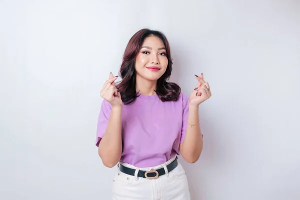 薄紫のTシャツを着た魅力的な若いアジア人女性が幸せを感じ ロマンチックな形のハートジェスチャーは優しい気持ちを表現しています — ストック写真