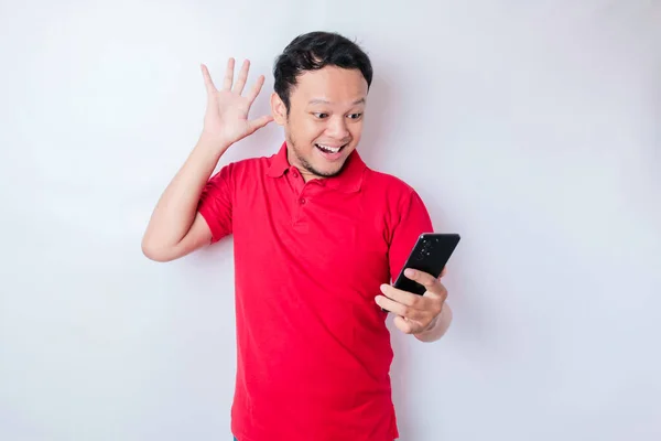 Förvånad Asiatisk Man Bär Röd Shirt Pekar Sin Smartphone Isolerad — Stockfoto
