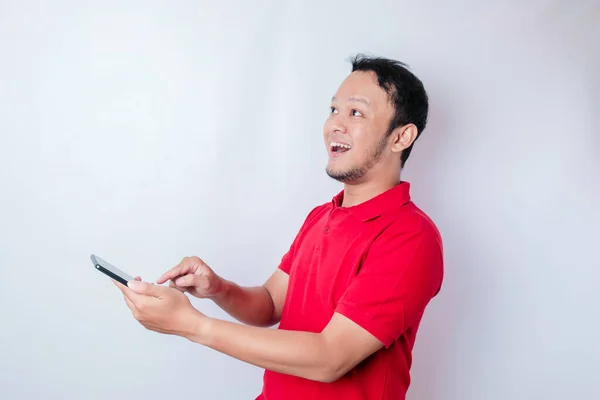 Förvånad Asiatisk Man Bär Röd Shirt Pekar Sin Smartphone Isolerad — Stockfoto