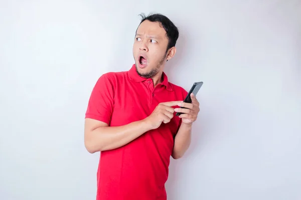 Surprised Asian Man Wearing Red Shirt Pointing His Smartphone Isolated — Stock Photo, Image