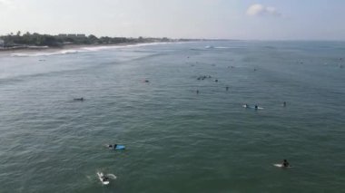 Aerial view of people surfing on waves with surfboards when vacation in Bali, Indonesia .