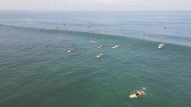 Aerial view of people surfing on waves with surfboards when vacation in Bali, Indonesia .