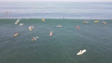 Aerial view of people surfing on waves with surfboards when vacation in Bali, Indonesia .