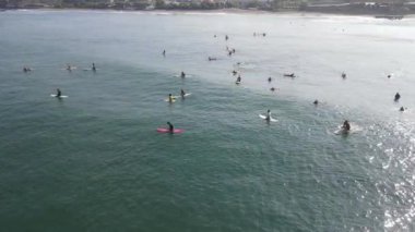 Aerial view of people surfing on waves with surfboards when vacation in Bali, Indonesia .