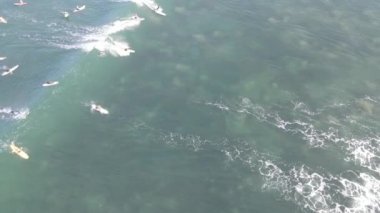 Aerial view of people surfing on waves with surfboards when vacation in Bali, Indonesia .