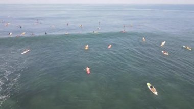 Aerial view of people surfing on waves with surfboards when vacation in Bali, Indonesia .