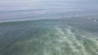 Aerial view of people surfing on waves with surfboards when vacation in Bali, Indonesia .